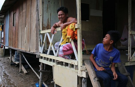 Yusop Saad and his son sitting in front of their home. (Photo by Zan Azlee)